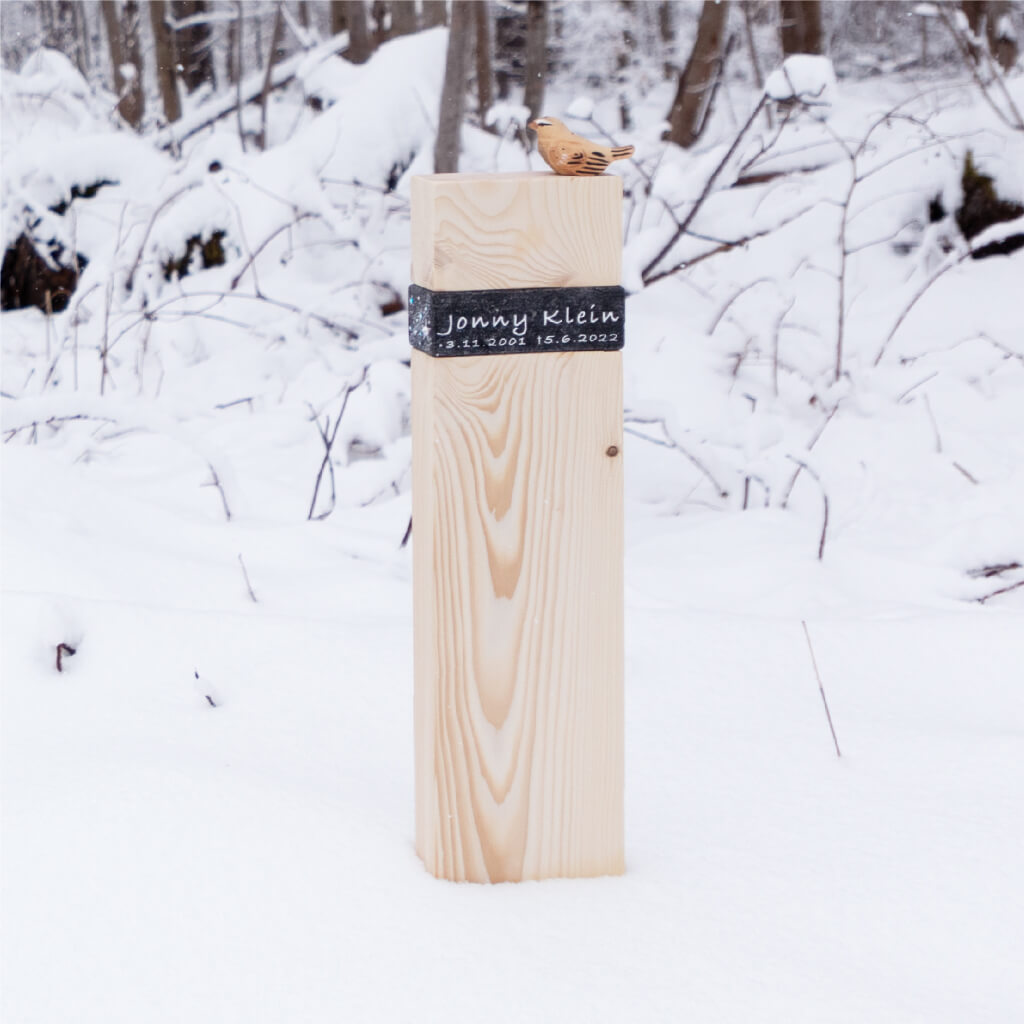 Übergansholz Jonny als moderenes Holzkreuz mit Naturstein im Winter bei Eis und Schnee gesetzt