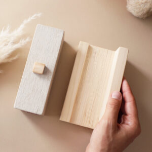 Namensstein von ÜHolz® Jonny wird behutsam aufgestellt – stimmungsvolle Szene in Beige